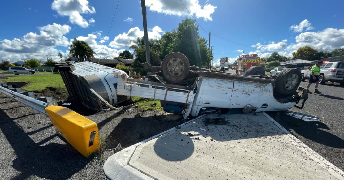 Man walks from wreckage after ute towing horse float flips